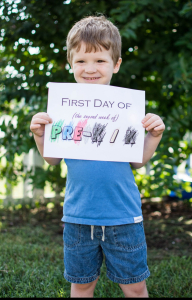 Jessica's youngest poses with a First Day of Pre-K sign.